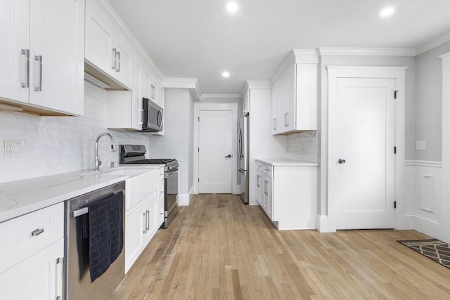 39 Pond St, Framingham, MA 01702 - kitchen with appliances with stainless steel finishes, white cabinetry, light wood-type flooring, recessed lighting, and crown molding