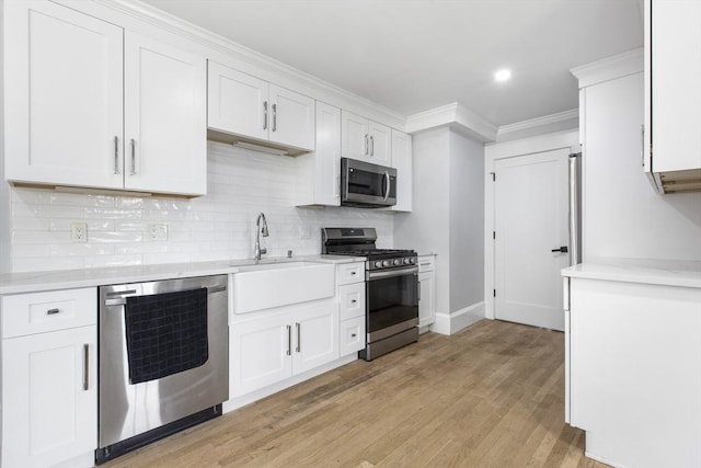 39 Pond St, Framingham, MA 01702 - kitchen with stainless steel appliances, a sink, light countertops, backsplash, and light wood-style flooring
