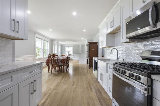 39 Pond St, Framingham, MA 01702 - kitchen featuring stainless steel appliances, crown molding, a decorative wall, light stone counters, and wainscoting