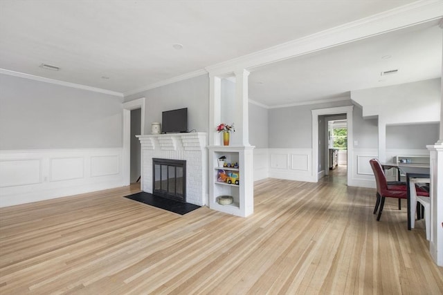 39 Pond St, Framingham, MA 01702 - living room featuring a brick fireplace, light wood-style flooring, crown molding, a decorative wall, and wainscoting