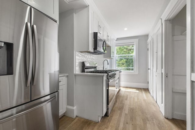39 Pond St, Framingham, MA 01702 - kitchen with stainless steel appliances, baseboards, light wood-type flooring, white cabinetry, and recessed lighting