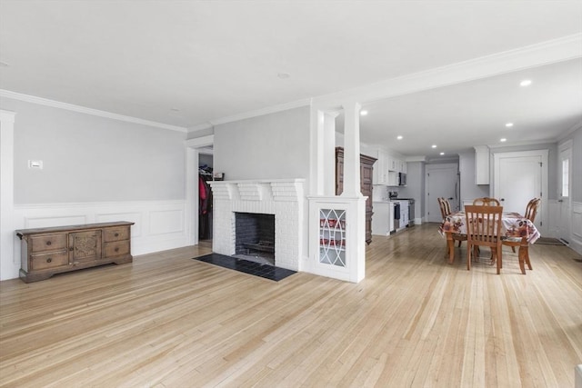 39 Pond St, Framingham, MA 01702 - living area with light wood finished floors, a brick fireplace, a decorative wall, ornamental molding, and a wainscoted wall