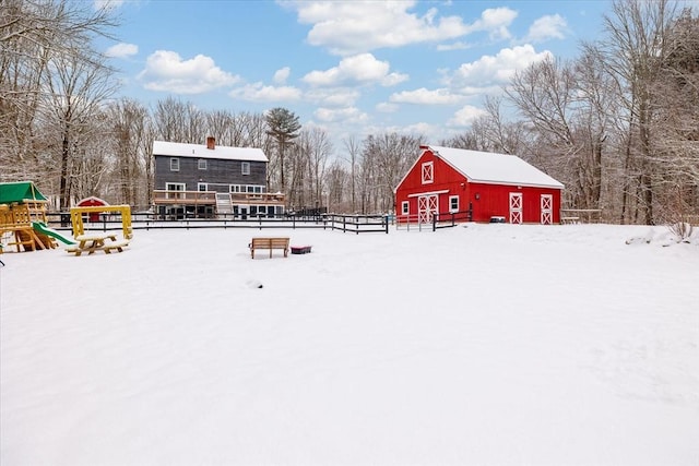 snowy yard with a playground and an outbuilding