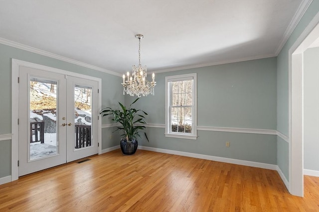 unfurnished dining area featuring baseboards, visible vents, ornamental molding, french doors, and light wood-type flooring