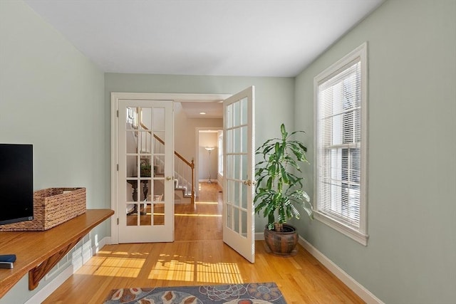 doorway to outside with french doors, a healthy amount of sunlight, baseboards, and light wood finished floors