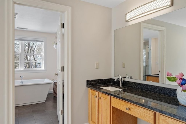 bathroom with a freestanding tub, tile patterned floors, visible vents, and vanity