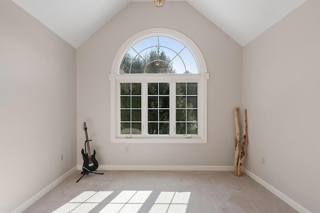 unfurnished room featuring light colored carpet, vaulted ceiling, and baseboards