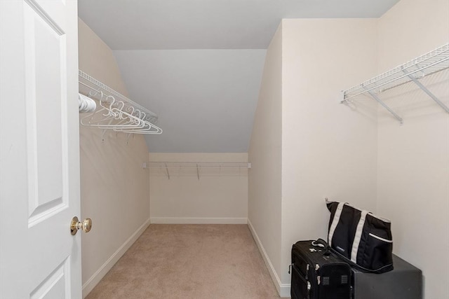 walk in closet with light carpet and vaulted ceiling