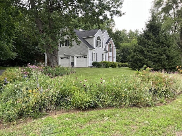 view of side of property featuring a garage and a lawn