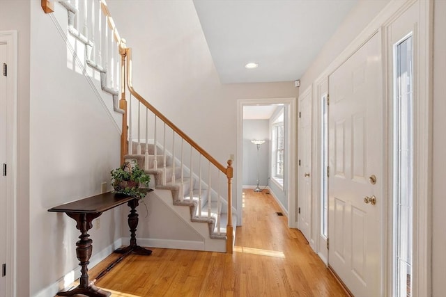 foyer featuring light wood-type flooring, stairs, and baseboards