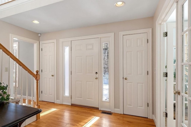 foyer entrance featuring recessed lighting, visible vents, light wood-style floors, stairs, and plenty of natural light