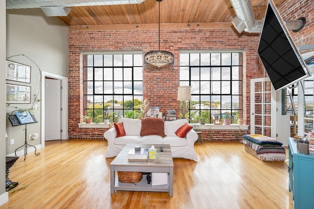 living room with brick wall, light hardwood / wood-style flooring, and a wealth of natural light