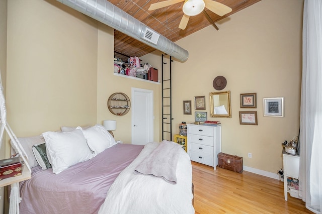 bedroom featuring light wood-type flooring, a towering ceiling, ceiling fan, and wooden ceiling