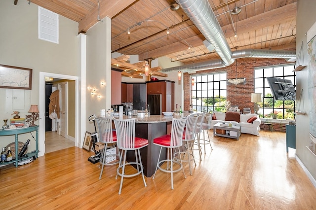 kitchen with wood ceiling, brick wall, kitchen peninsula, a breakfast bar area, and light hardwood / wood-style flooring