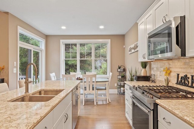 kitchen featuring appliances with stainless steel finishes, a sink, light wood-style flooring, tasteful backsplash, and recessed lighting