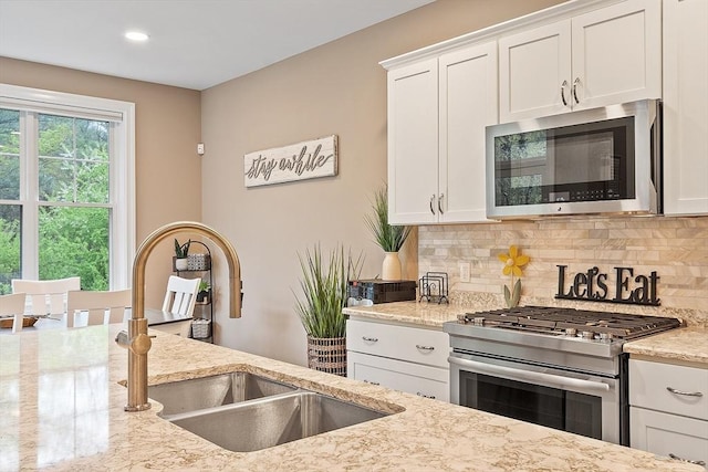 kitchen with stainless steel appliances, decorative backsplash, a sink, white cabinetry, and recessed lighting