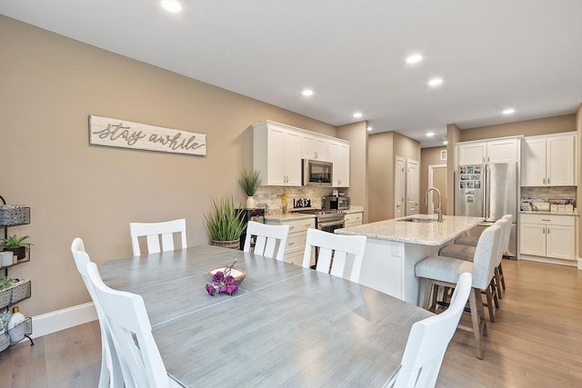 dining area featuring light wood-style floors, baseboards, and recessed lighting