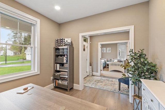 corridor featuring light wood finished floors and baseboards
