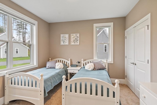 bedroom with light carpet, multiple windows, baseboards, and a closet