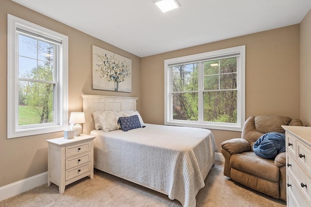 bedroom with multiple windows, light carpet, and baseboards