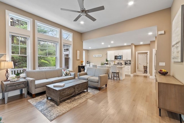 living area featuring light wood-style floors, ceiling fan, and recessed lighting