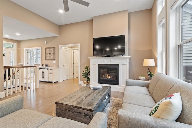 living area featuring ceiling fan, light wood-style flooring, a glass covered fireplace, and recessed lighting