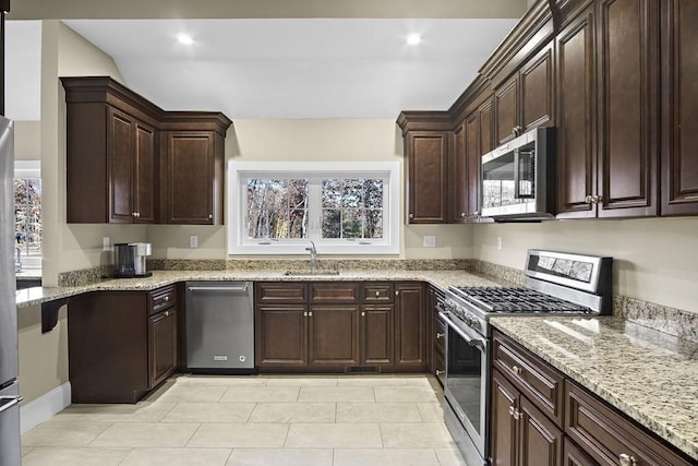 kitchen with light stone counters, sink, stainless steel appliances, and dark brown cabinets