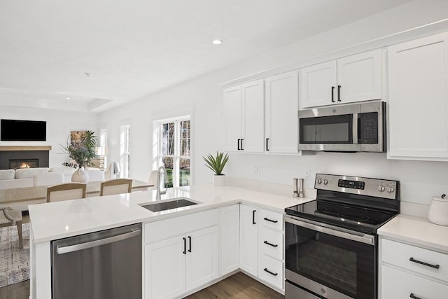 kitchen featuring dark wood-type flooring, white cabinets, sink, kitchen peninsula, and stainless steel appliances