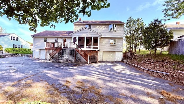13 Ridgewood Cir, Lawrence, NY 10843 - view of front of house with stairway, a chimney, asphalt driveway, an attached garage, and a sunroom