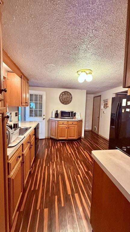 13 Ridgewood Cir, Lawrence, NY 10843 - kitchen with black refrigerator with ice dispenser, stainless steel microwave, brown cabinetry, light countertops, and a textured ceiling
