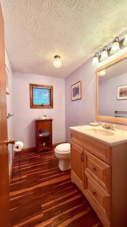 13 Ridgewood Cir, Lawrence, NY 10843 - half bathroom with vanity, toilet, wood finished floors, a textured ceiling, and baseboards