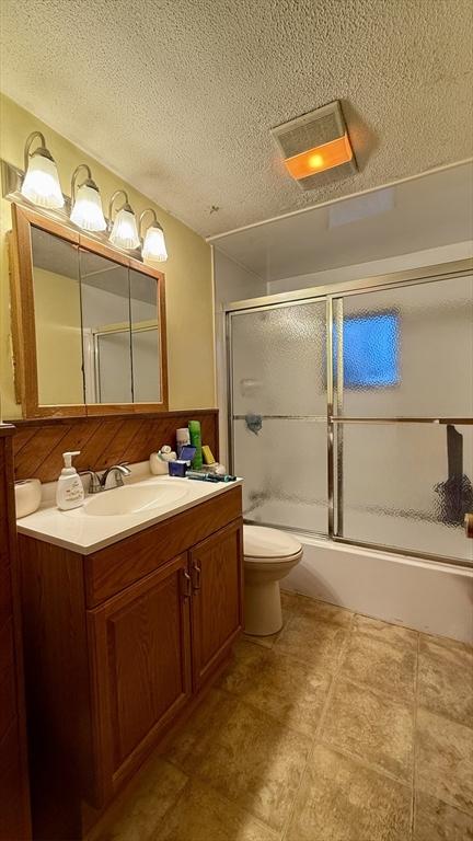 13 Ridgewood Cir, Lawrence, NY 10843 - bathroom featuring vanity, a textured ceiling, shower / bath combination with glass door, and toilet