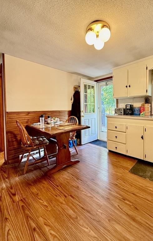 13 Ridgewood Cir, Lawrence, NY 10843 - kitchen with light wood-style floors, a textured ceiling, a wainscoted wall, white cabinets, and light countertops