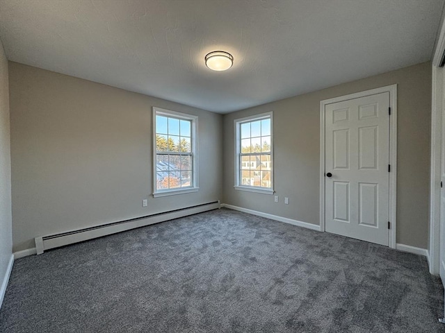 empty room with a baseboard radiator, a textured ceiling, and dark colored carpet