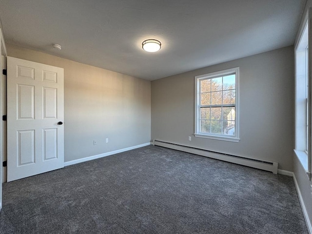 spare room featuring dark colored carpet and a baseboard heating unit