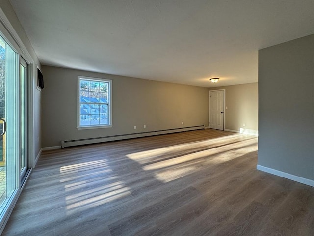 empty room featuring wood-type flooring and a baseboard heating unit