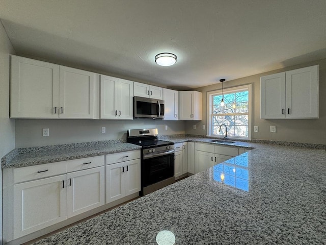 kitchen featuring pendant lighting, sink, light stone countertops, white cabinetry, and stainless steel appliances