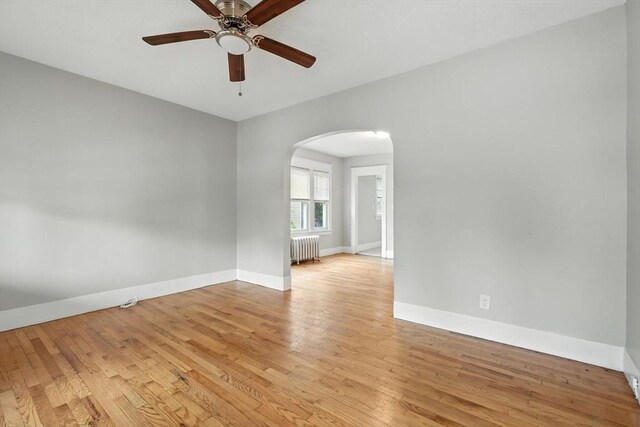 31-33 Dorset St, Springfield, MA 01108 - empty room featuring radiator, arched walkways, a ceiling fan, and light wood finished floors