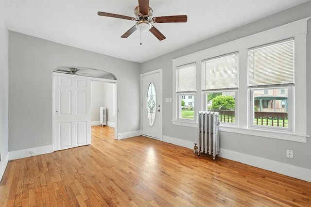 31-33 Dorset St, Springfield, MA 01108 - entrance foyer featuring radiator heating unit, a ceiling fan, light wood-style flooring, and arched walkways
