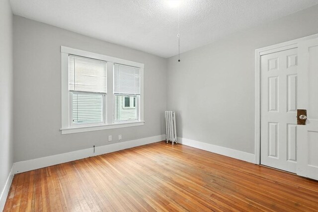 31-33 Dorset St, Springfield, MA 01108 - empty room with radiator, light wood-style floors, and a textured ceiling