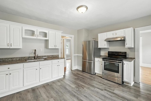 31-33 Dorset St, Springfield, MA 01108 - kitchen with appliances with stainless steel finishes, under cabinet range hood, white cabinets, light wood-style flooring, and dark stone countertops