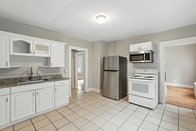 31-33 Dorset St, Springfield, MA 01108 - kitchen featuring stainless steel appliances, white cabinets, light tile patterned flooring, a textured ceiling, and glass insert cabinets