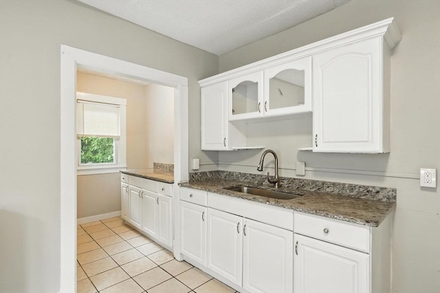 31-33 Dorset St, Springfield, MA 01108 - kitchen with white cabinetry, light tile patterned floors, dark stone countertops, and glass insert cabinets