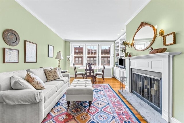 living room featuring a fireplace with flush hearth, light wood-type flooring, baseboards, and ornamental molding