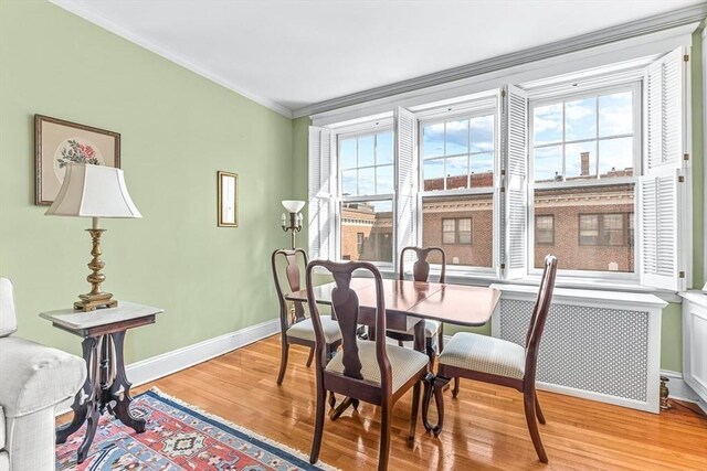 dining space with light wood-type flooring, baseboards, and ornamental molding