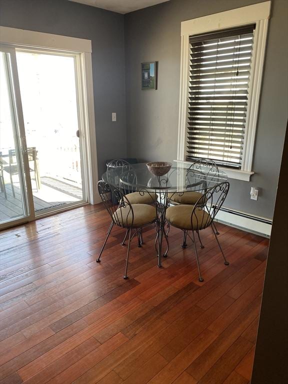 dining space featuring a baseboard heating unit, a healthy amount of sunlight, and hardwood / wood-style floors