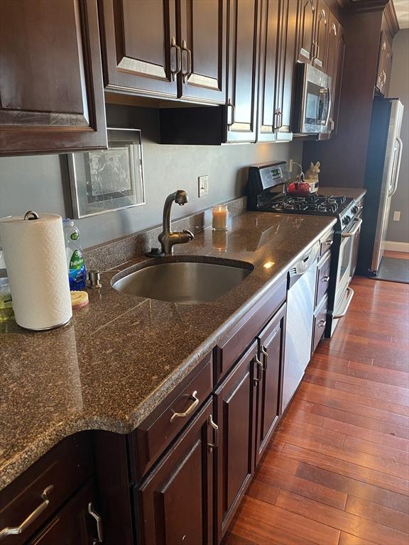 kitchen featuring dark wood-type flooring, dark brown cabinetry, stainless steel appliances, and sink