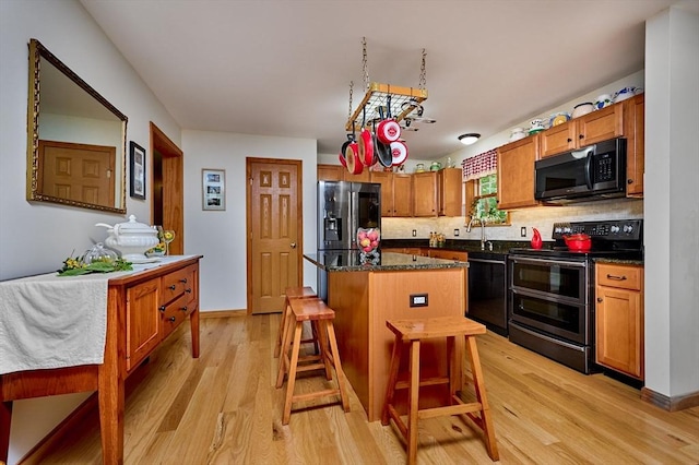 43 Ridge Rd, Erving, MA 01344 - kitchen with stainless steel appliances, light wood-style floors, a center island, a breakfast bar area, and tasteful backsplash