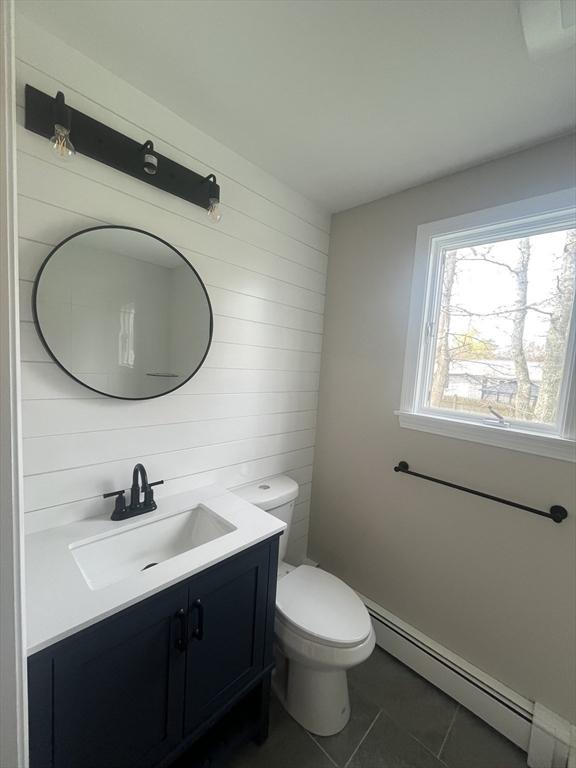 23 Town Hall Ave, Yarmouth, MA 02664 - bathroom with tile patterned floors, wooden walls, toilet, vanity, and baseboard heating