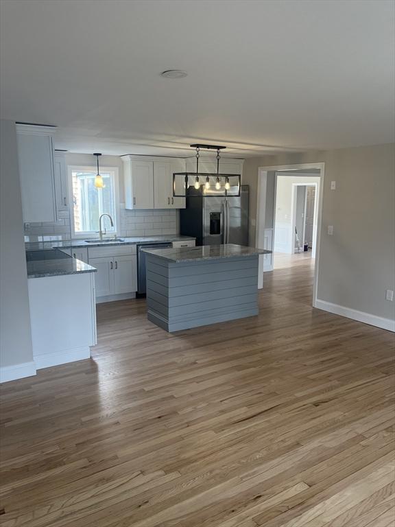 23 Town Hall Ave, Yarmouth, MA 02664 - kitchen featuring stainless steel appliances, a center island, a sink, light wood-type flooring, and pendant lighting